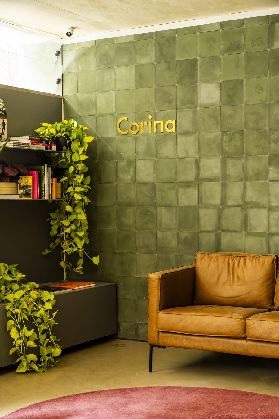 Lounge de leitura com parede em azulejo verde e a assinatura Corina